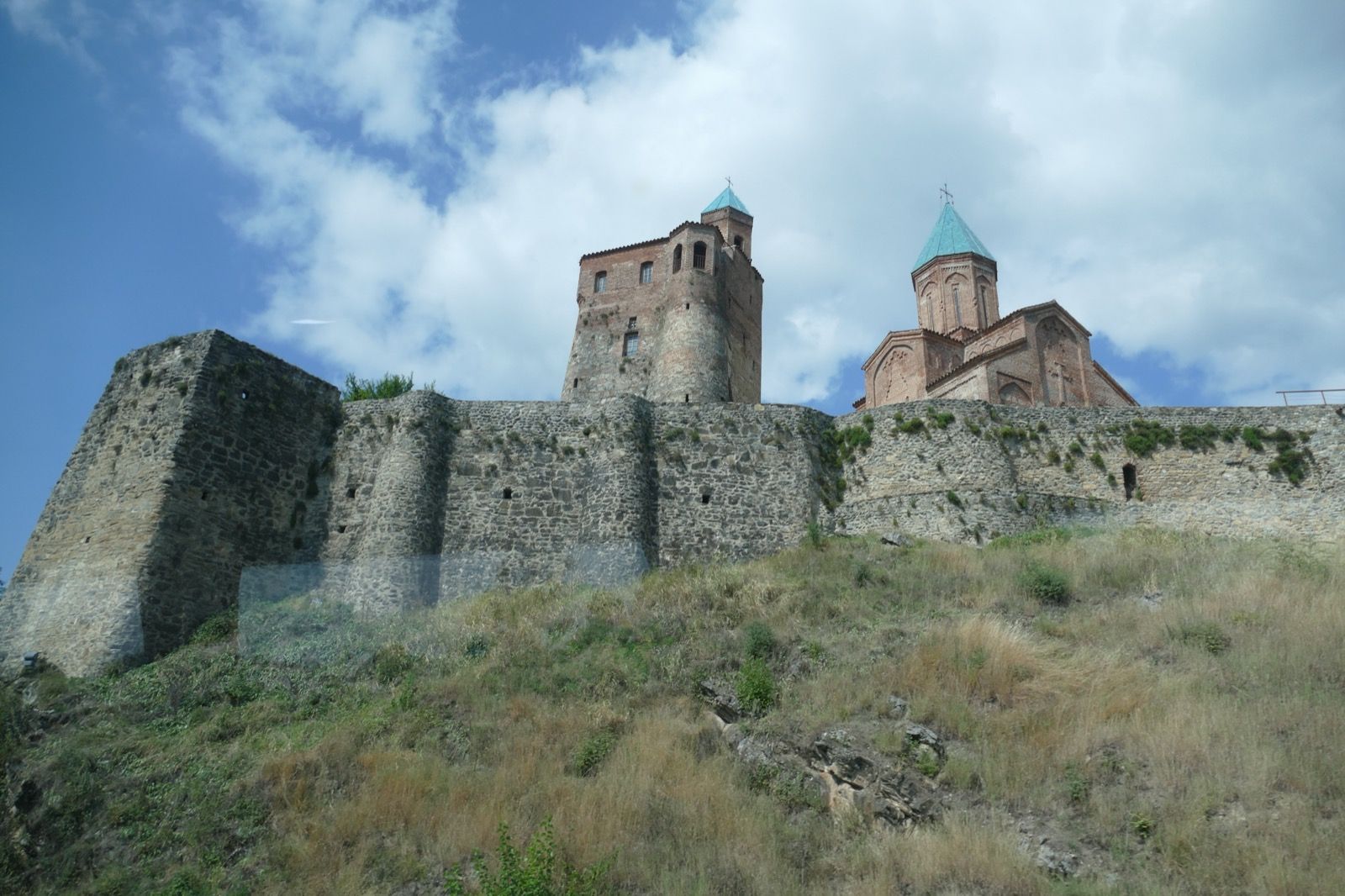 Cihlový kostel archandělů a věž komplexu Gremi na kopci nad Alazanským údolím v Kachetii